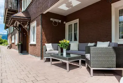 a patio with chairs and a table with flowers on it at Schwendi Lodge in Unterwasser