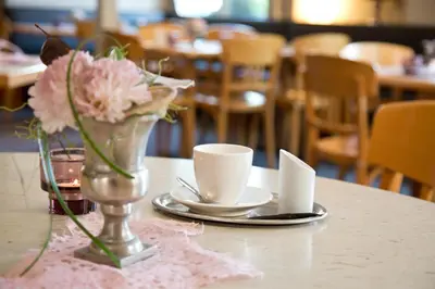a table with a vase of flowers and two cups at Hotel Buchserhof in Buchs