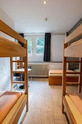 a room with three bunk beds and a desk at Kreuzlingen Youth Hostel in Kreuzlingen