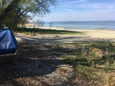 a road next to a beach with a blue tarp at Bodensee Moosburg Biohof am See in Güttingen