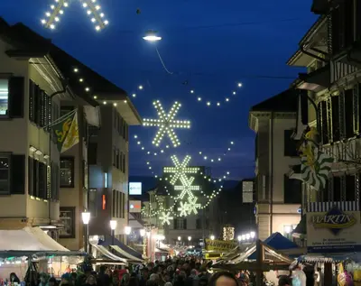 a crowd of people walking down a street with christmas lights at Gasthof Eisenbahn in Weinfelden