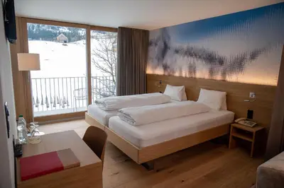 a lake in the middle of a field with mountains at Hotel Stump's Alpenrose in Wildhaus