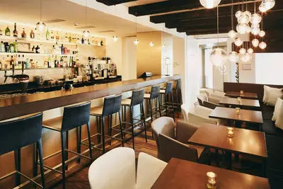 a restaurant with tables and chairs and a bar at Hotel Uzwil in Uzwil