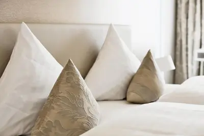 a white bed with white pillows on it at Hotel Uzwil in Uzwil
