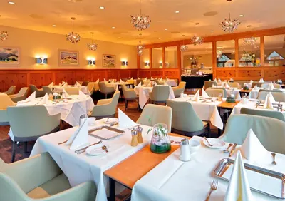 a restaurant with tables and chairs and chandeliers at Lodge Hof Weissbad in Weissbad