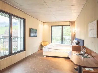 a bedroom with a bed and a table and windows at Lodge Hof Weissbad in Weissbad