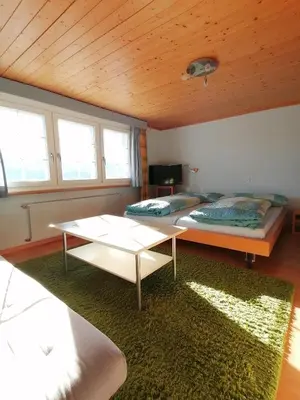 a living room with two beds and a table at Gasthaus Bären Schlatt in Appenzell