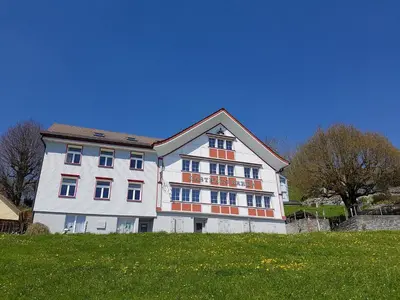 a large white building on top of a green field at Gasthaus Bären Schlatt in Appenzell