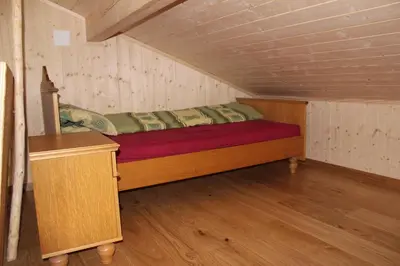 a small bedroom with a bed in a attic at Chalet Nueschwendi in Ebnat