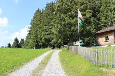 a dirt road next to a fence and a flag at Chalet Nueschwendi in Ebnat