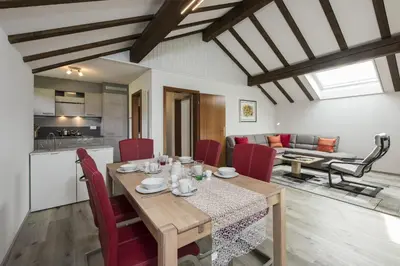 a dining room and living room with a table and red chairs at Bella Vista in Wildhaus