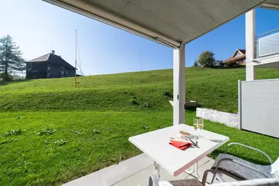 a white table on a patio with a view of a hill at Sunnewies in Wildhaus