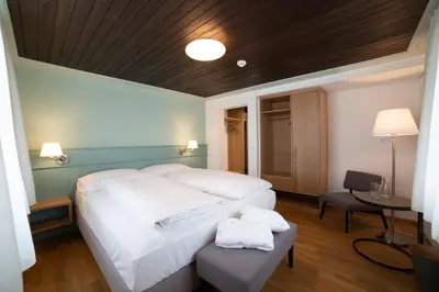 a bedroom with a large white bed and a table at Gasthaus Friedegg in Wildhaus