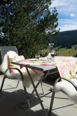 a table with glasses of wine and a vase on it at Steinrüti in Wildhaus