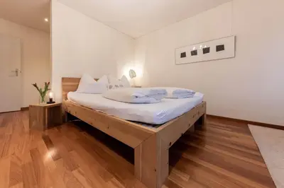 a bedroom with a wooden bed with white sheets at Schwalbennest in Wildhaus