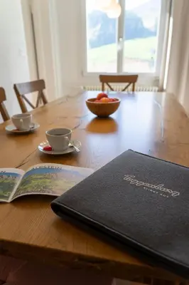 a book on a wooden table with a bowl of fruit at Lisighaus in Wildhaus