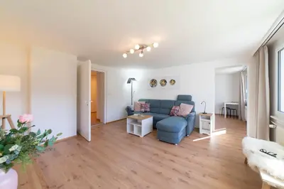 a living room with a blue couch and wooden floors at Lisighaus in Wildhaus