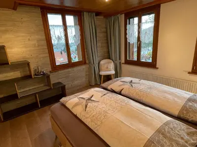 a bedroom with two beds and a desk and windows at Hälmli in Heiden