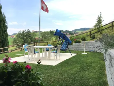 a table and chairs in a garden with a flag at Hälmli in Heiden