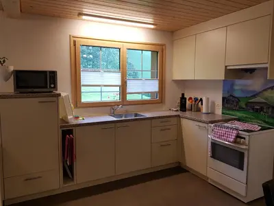 a kitchen with white cabinets and a sink and a microwave at Ferien im Gugger in Nesslau