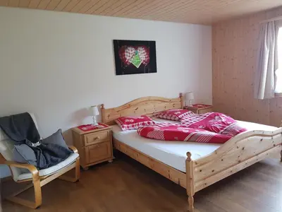 a bedroom with a bed with red pillows and a chair at Ferien im Gugger in Nesslau