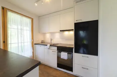 a kitchen with white cabinets and a black appliance at Schönau in Wildhaus