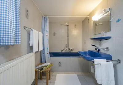 a bathroom with a blue sink and a tub at Chalet Ritornell in Wildhaus