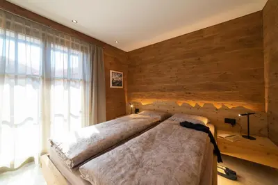 a bedroom with a large bed with a wooden wall at Chalet Hinterrugg in Wildhaus