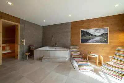 a bathroom with a tub and a sink and chairs at Chalet Hinterrugg in Wildhaus
