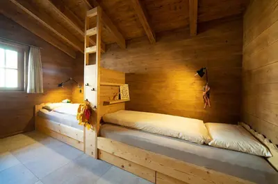 two beds in a room with wooden walls at Chalet Chäserrugg in Wildhaus