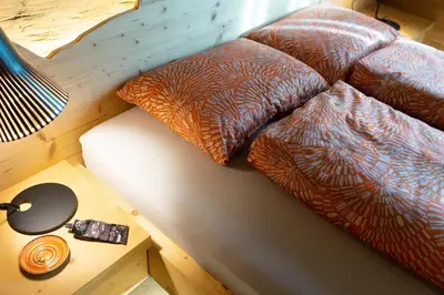 a bed with three pillows on it with a table at Chalet Chäserrugg in Wildhaus