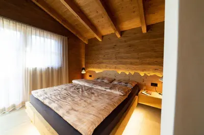 a large bed in a room with a wooden wall at Chalet Chäserrugg in Wildhaus