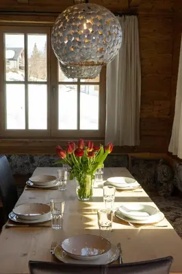 a table with a vase of flowers and a large light fixture at Chalet Zuestoll in Wildhaus