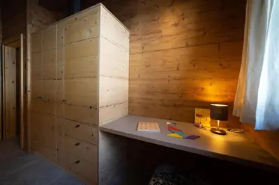 a room with a wooden wall with a desk with a lamp at Chalet Schafberg in Wildhaus