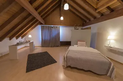a bedroom with a large bed in a room with wooden ceilings at BnB Alpenblick in Lütisburg
