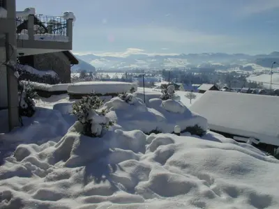 a yard covered in snow next to a house at BnB Alpenblick in Lütisburg