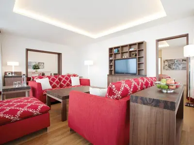 a living room with red furniture and a television at Oberwaid - Das Hotel. in St. Gallen