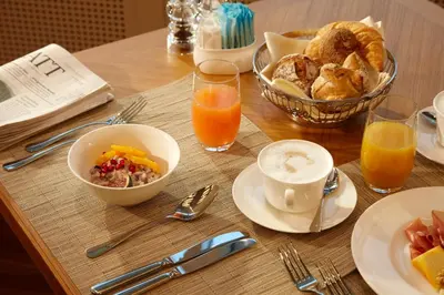 a table with a breakfast of breakfast foods and orange juice at Oberwaid - Das Hotel. in St. Gallen
