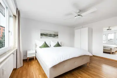 a white bedroom with a bed and a ceiling fan at SOHO F !Gratis Parken, Free Parking! in Kreuzlingen