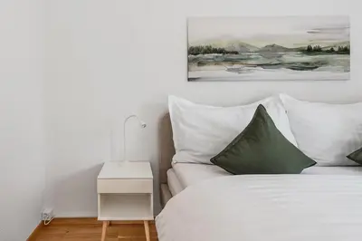 a bedroom with a bed with white sheets and green pillows at SOHO F !Gratis Parken, Free Parking! in Kreuzlingen