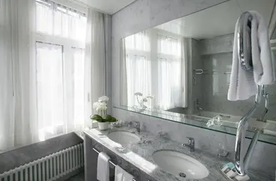 a bathroom with two sinks and a large mirror at Einstein St. Gallen in St. Gallen