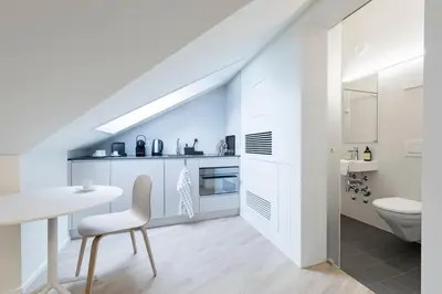 a white kitchen with a table and a chair at Dom Studios in St. Gallen