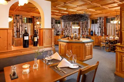 a dining room with a table and bottles of wine at Hirschen Guesthouse - Village Hotel in Wildhaus