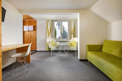 a living room with a green couch and a table at Hirschen Guesthouse - Village Hotel in Wildhaus