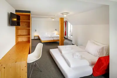 a living room with a white couch and a bedroom at Hirschen Guesthouse - Village Hotel in Wildhaus