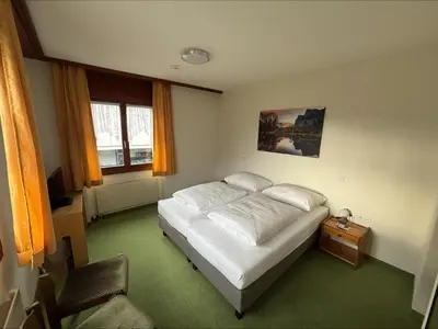 a bedroom with a white bed and a table and window at Hirschen Guesthouse - Village Hotel in Wildhaus