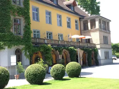 a building with a balcony with bushes in front of it at Schloss Brunnegg in Kreuzlingen