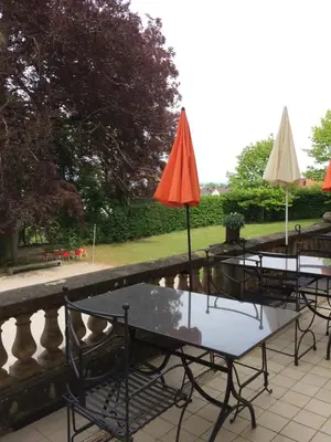 a table with chairs and umbrellas next to a pond at Schloss Brunnegg in Kreuzlingen