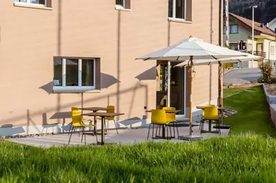 a patio with tables and chairs and an umbrella at Neuhof Gäste-& Schokohaus in Appenzell