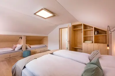 a bedroom with two beds and cabinets and a skylight at Neuhof Gäste-& Schokohaus in Appenzell